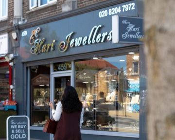 Woman standing outside a jewelry store named 'Hari Jewellers' on a street.